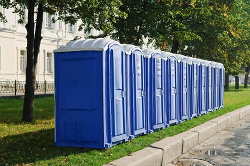 porta potties on the grass next to a sidewalk